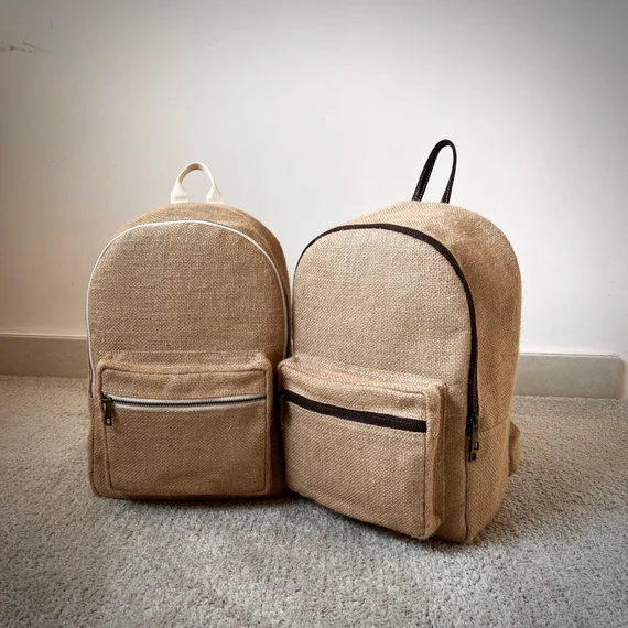 A jute backpack with leather bottom placed on a bench with books partially visible inside