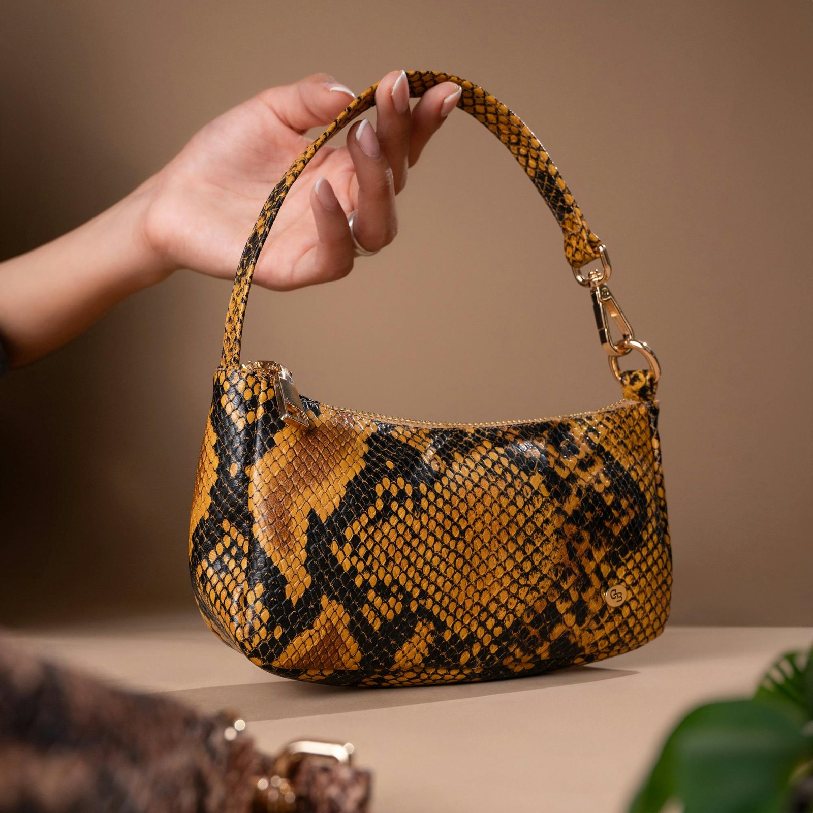 A stylish snake print handbag held professionally, showcasing luxury fashion.