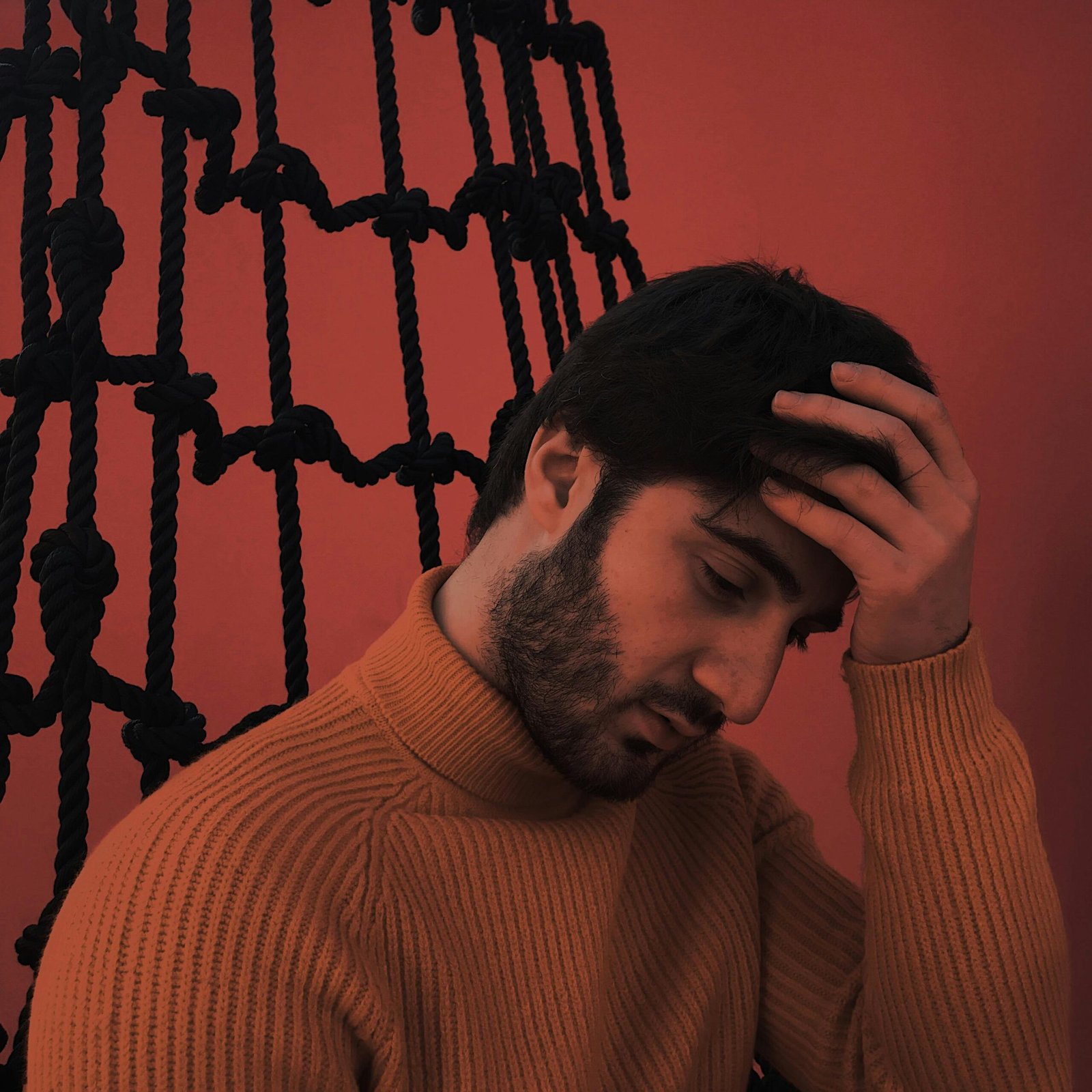 Moody portrait of a man in a knit sweater, deep in thought, indoors.